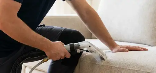 Professional upholstery cleaner deep-cleaning a fabric sofa with a handheld extraction tool, Cape Coral, FL.